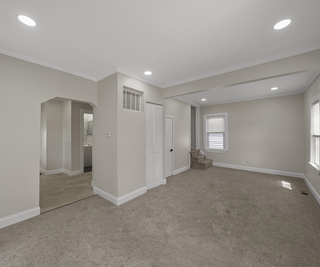 carpeted spare room featuring crown molding, arched walkways, recessed lighting, baseboards, and visible vents