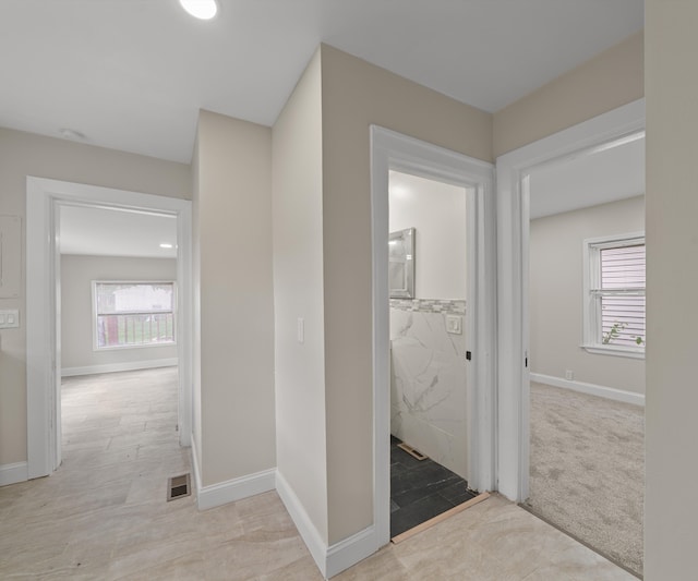 hall featuring a healthy amount of sunlight, baseboards, and visible vents