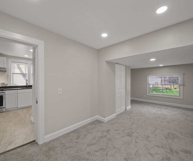 below grade area with recessed lighting, baseboards, light carpet, and a sink