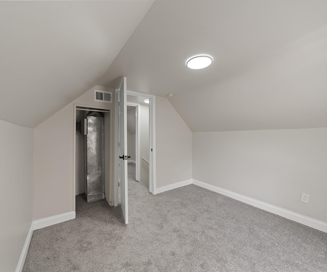 additional living space with baseboards, carpet, lofted ceiling, and visible vents