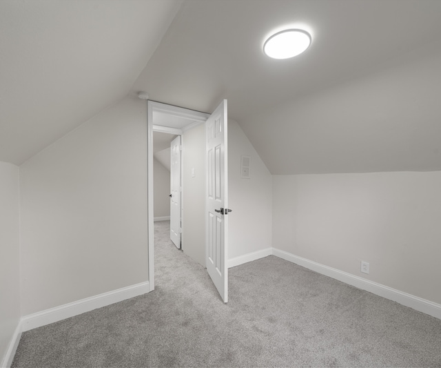 additional living space featuring carpet floors, baseboards, and vaulted ceiling