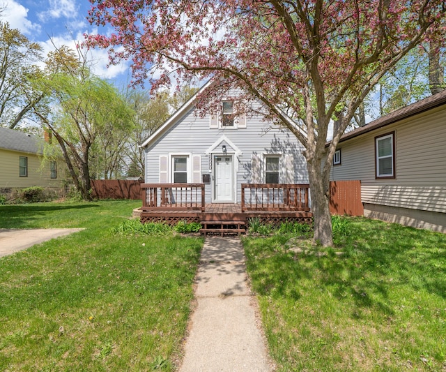 bungalow-style home with fence, a deck, and a front yard