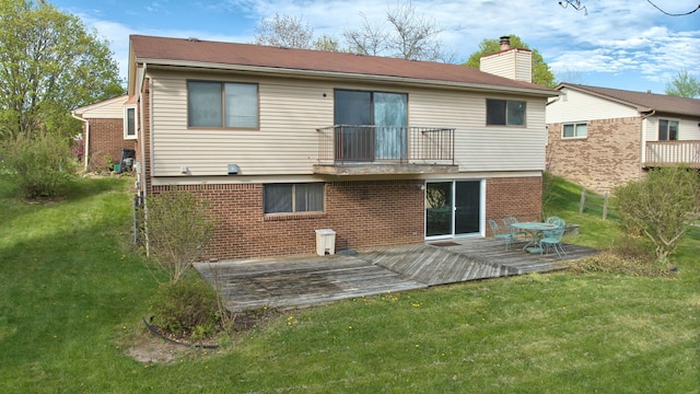 rear view of house with a yard, brick siding, a chimney, and a balcony