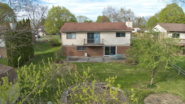 rear view of house featuring brick siding, a lawn, a balcony, and a chimney