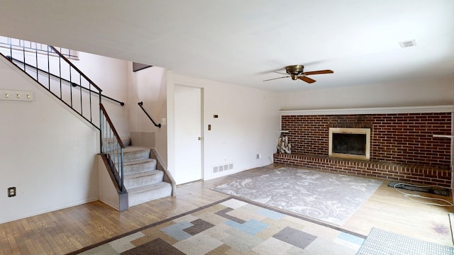 unfurnished living room with stairs, a ceiling fan, visible vents, and wood finished floors