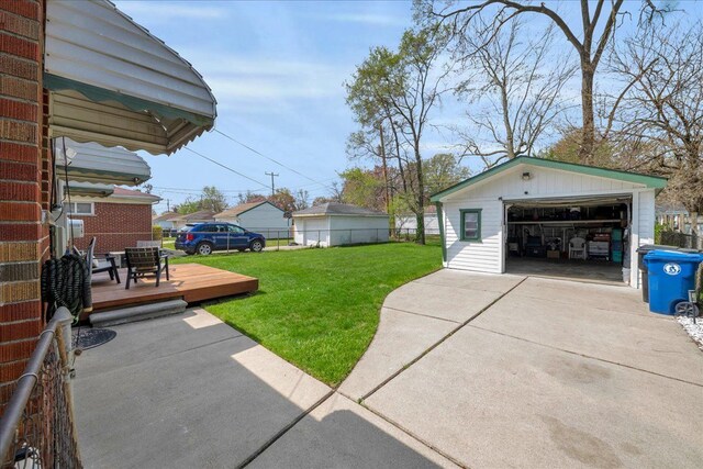 view of yard featuring a garage, a wooden deck, an outbuilding, and fence