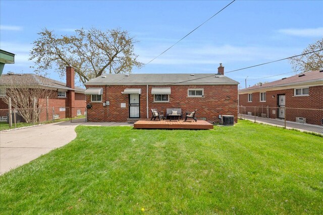 rear view of house with fence, brick siding, a deck, central AC unit, and a yard