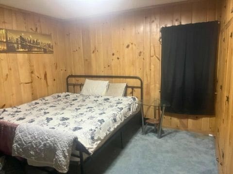 bedroom featuring wooden walls and carpet floors