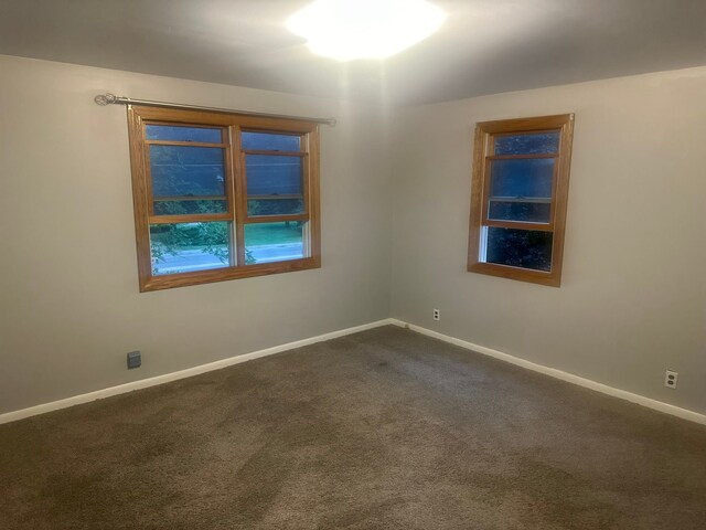 empty room with baseboards and dark colored carpet