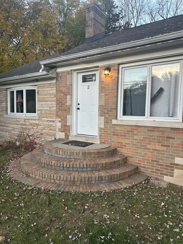property entrance with brick siding and a chimney