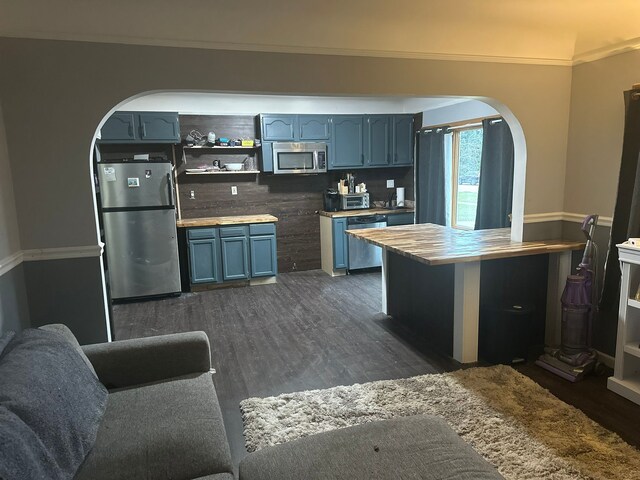 kitchen with crown molding, arched walkways, blue cabinetry, stainless steel appliances, and dark wood-type flooring