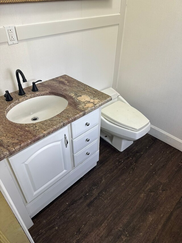 bathroom with vanity, baseboards, wood finished floors, and toilet