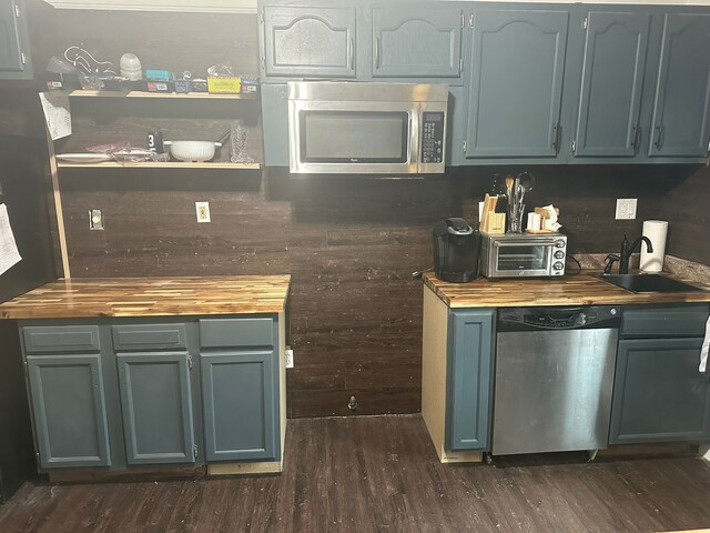 kitchen featuring stainless steel appliances, wood counters, dark wood finished floors, and a sink