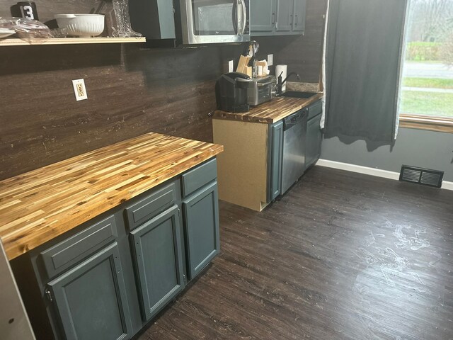 kitchen with dark wood-style flooring, stainless steel appliances, visible vents, and butcher block counters