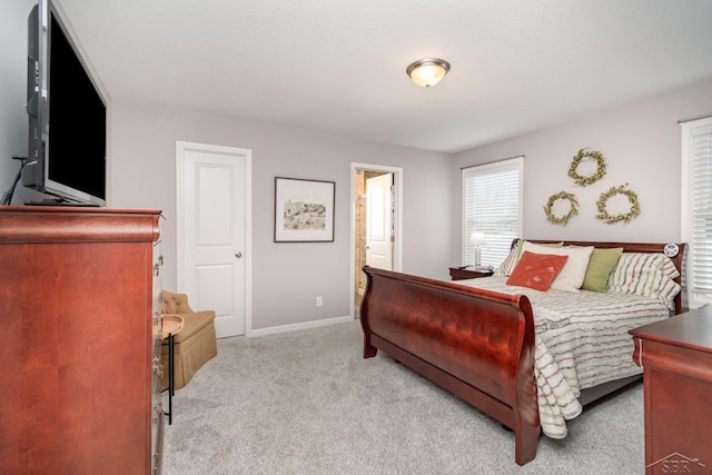 bedroom featuring baseboards, light carpet, and multiple windows