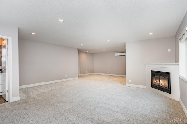unfurnished living room featuring carpet flooring, recessed lighting, a wall mounted AC, and a glass covered fireplace