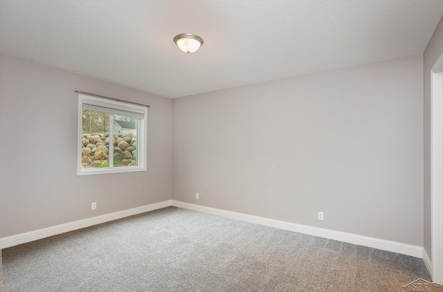 spare room featuring carpet floors and baseboards