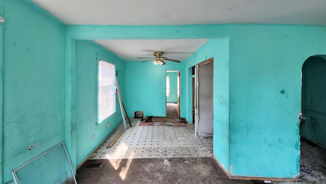 unfurnished room with arched walkways and a ceiling fan