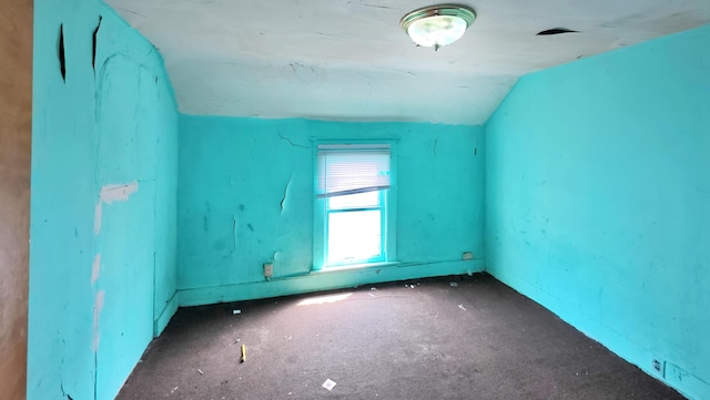 spare room featuring carpet floors and lofted ceiling