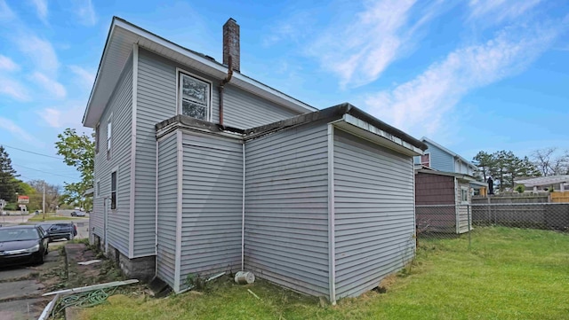 view of side of home featuring fence, a yard, and a chimney