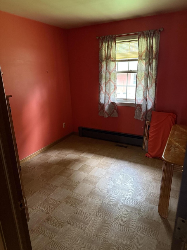 empty room featuring baseboards, a baseboard heating unit, and visible vents