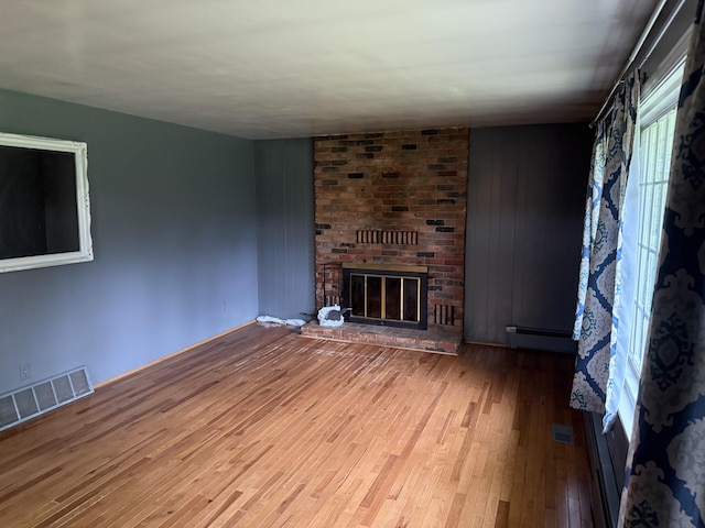 6411 Custer Rd, Carsonville, MI 48419 - unfurnished living room with a baseboard radiator, wood finished floors, and a fireplace