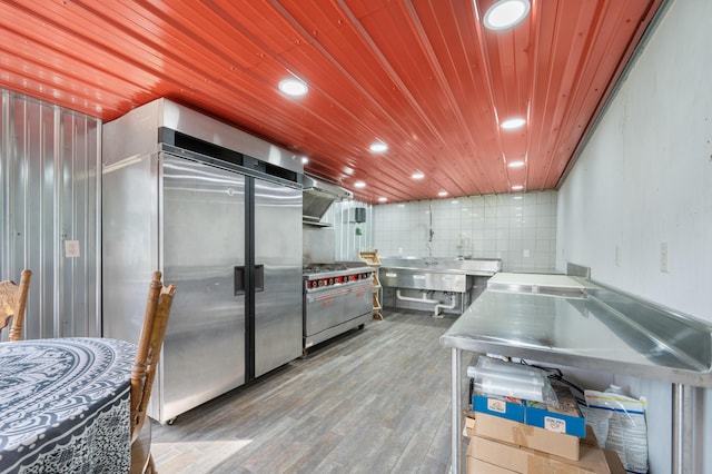 kitchen featuring wood finished floors, high quality appliances, recessed lighting, wooden ceiling, and stainless steel countertops