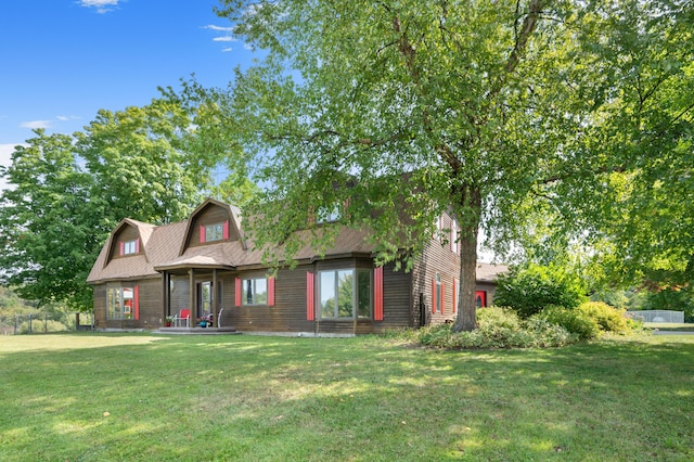 view of front facade with a gambrel roof and a front yard