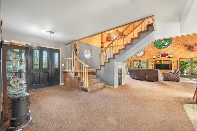 entryway featuring wood walls, carpet, and stairway