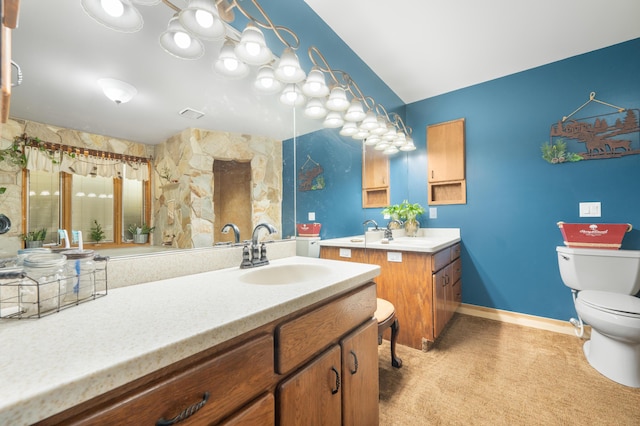 full bathroom featuring baseboards, a sink, two vanities, and toilet