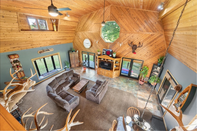 living room with a ceiling fan, high vaulted ceiling, wooden walls, and wooden ceiling