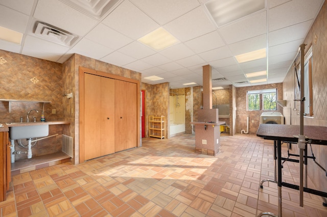 interior space featuring a sink, a drop ceiling, washer / clothes dryer, and visible vents