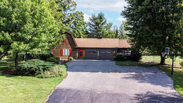view of front of house with an attached garage, a front yard, and aphalt driveway