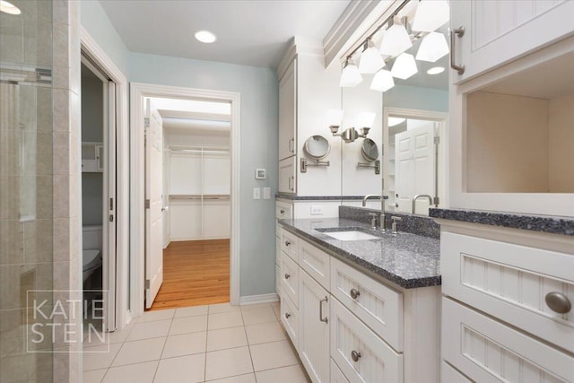 bathroom featuring tile patterned flooring, vanity, baseboards, toilet, and a spacious closet