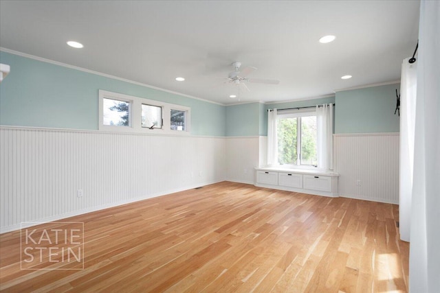 empty room featuring crown molding, wainscoting, ceiling fan, recessed lighting, and light wood finished floors
