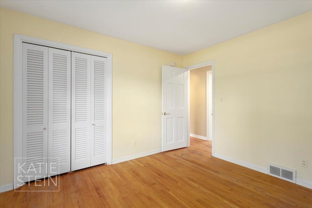 unfurnished bedroom featuring baseboards, a closet, wood finished floors, and visible vents