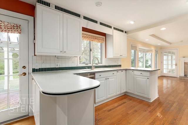 kitchen featuring backsplash, a peninsula, white cabinets, and a sink