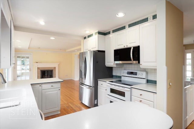 kitchen with tasteful backsplash, light wood-type flooring, a sink, a peninsula, and stainless steel appliances