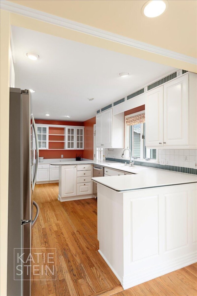 kitchen with white cabinetry, a peninsula, tasteful backsplash, and stainless steel appliances