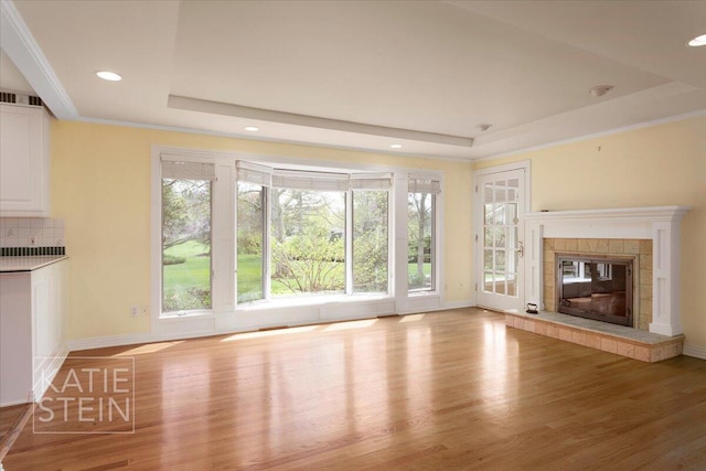 unfurnished living room featuring wood finished floors, a tray ceiling, and a wealth of natural light