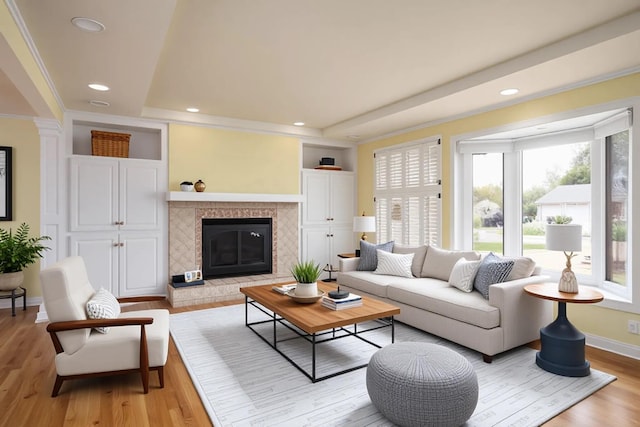 living room featuring light wood-style floors, a raised ceiling, baseboards, and recessed lighting