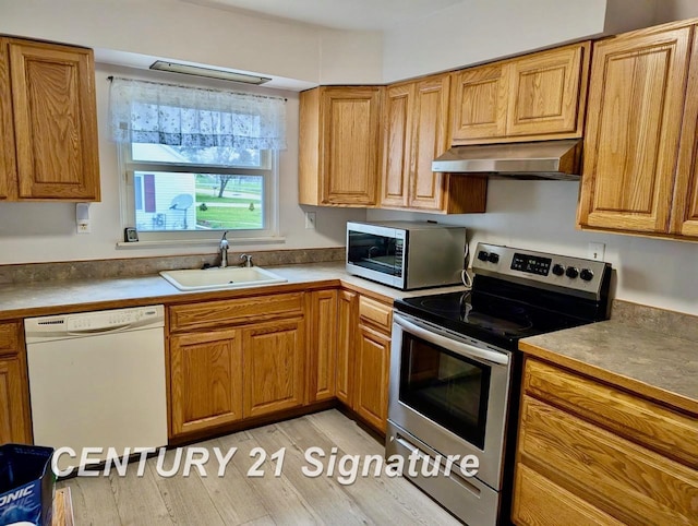 kitchen with a sink, brown cabinetry, light wood-style flooring, stainless steel appliances, and under cabinet range hood