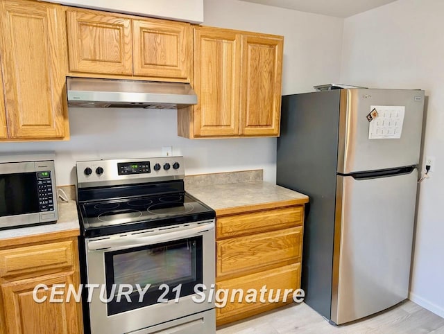 kitchen featuring light countertops, stainless steel appliances, ventilation hood, and light wood finished floors