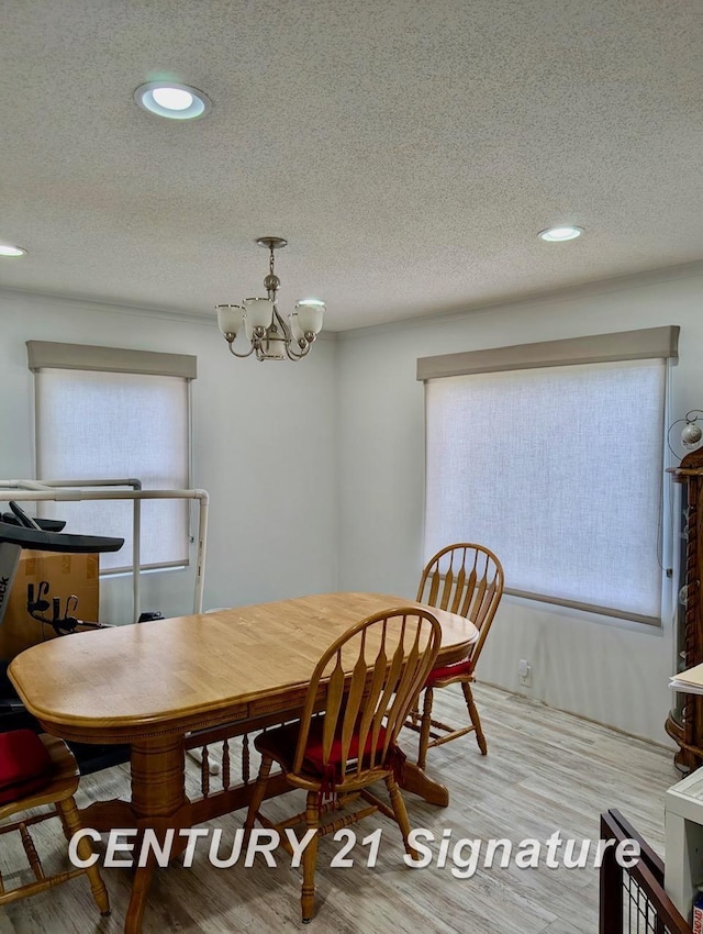 dining room with a textured ceiling, a chandelier, a wealth of natural light, and wood finished floors