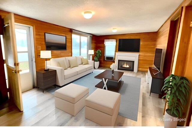 living area with plenty of natural light, a glass covered fireplace, and wooden walls