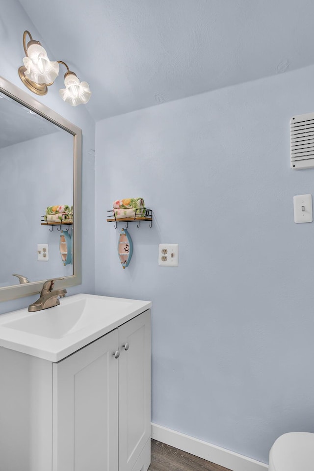 1704 Little Dr, Horton, MI 49246 - bathroom featuring vanity, baseboards, wood finished floors, and toilet
