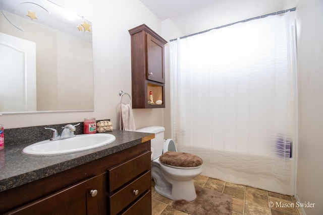 full bathroom featuring toilet, stone finish floor, shower / tub combo with curtain, and vanity