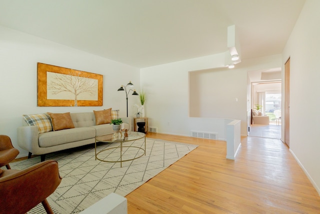 living room with baseboards, light wood-style flooring, and visible vents