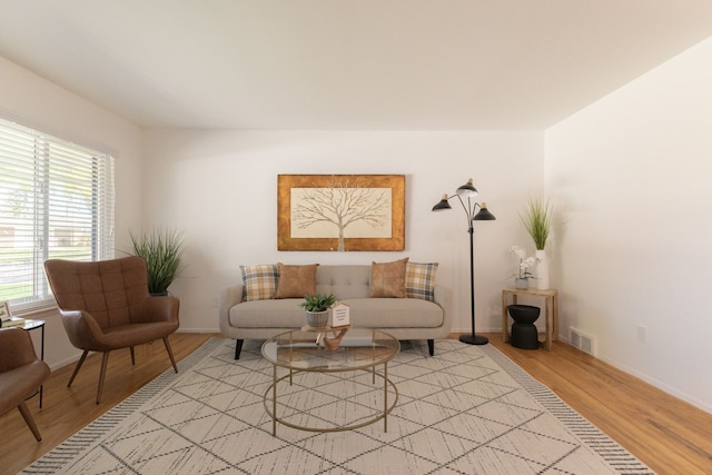 sitting room with light wood-style floors, baseboards, a wealth of natural light, and visible vents