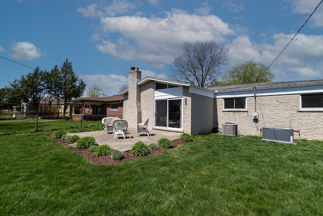 rear view of house featuring a lawn, a patio, and a chimney